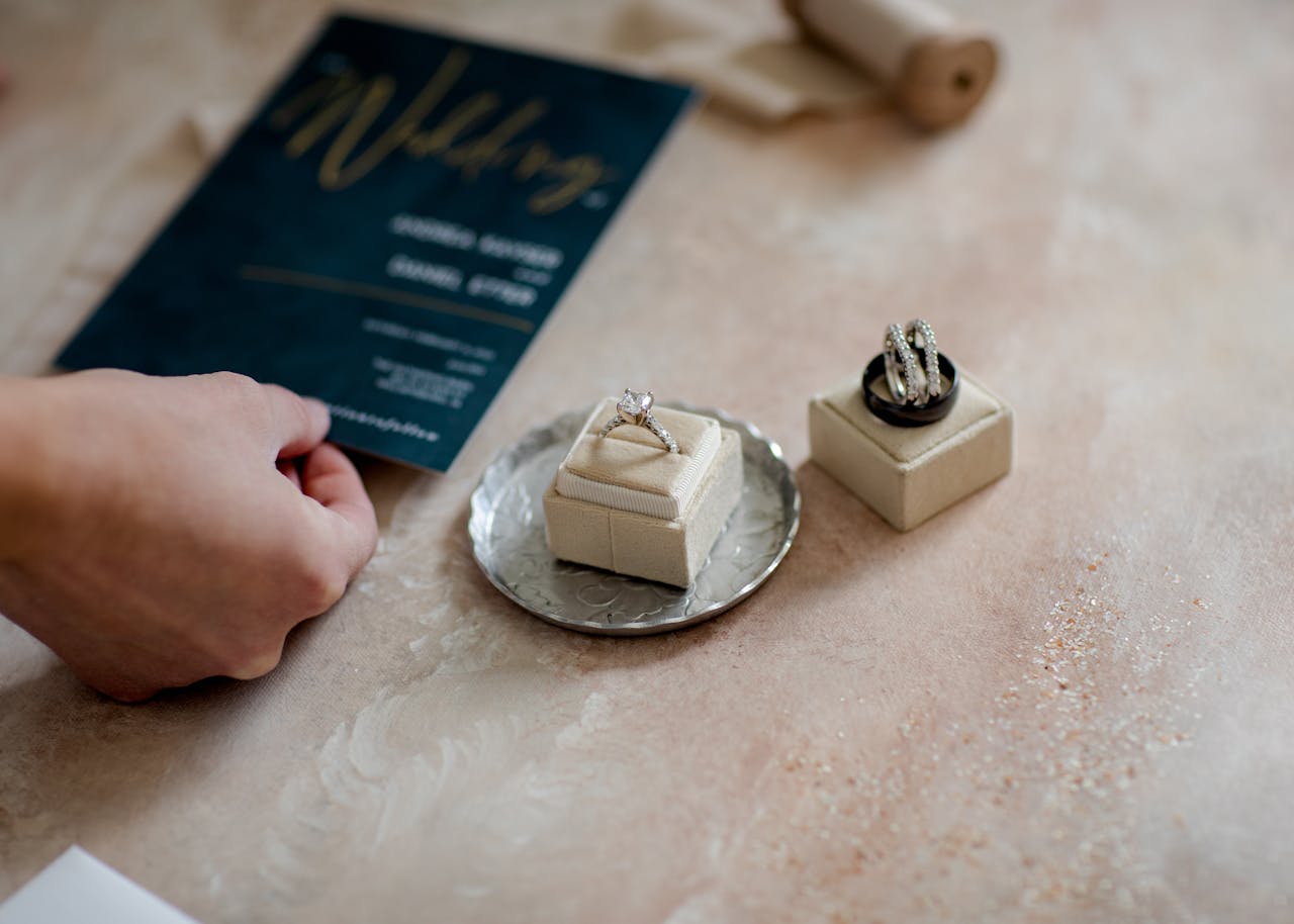 Close-up of wedding invitation and diamond rings on a tray, showcasing elegance and preparation.
